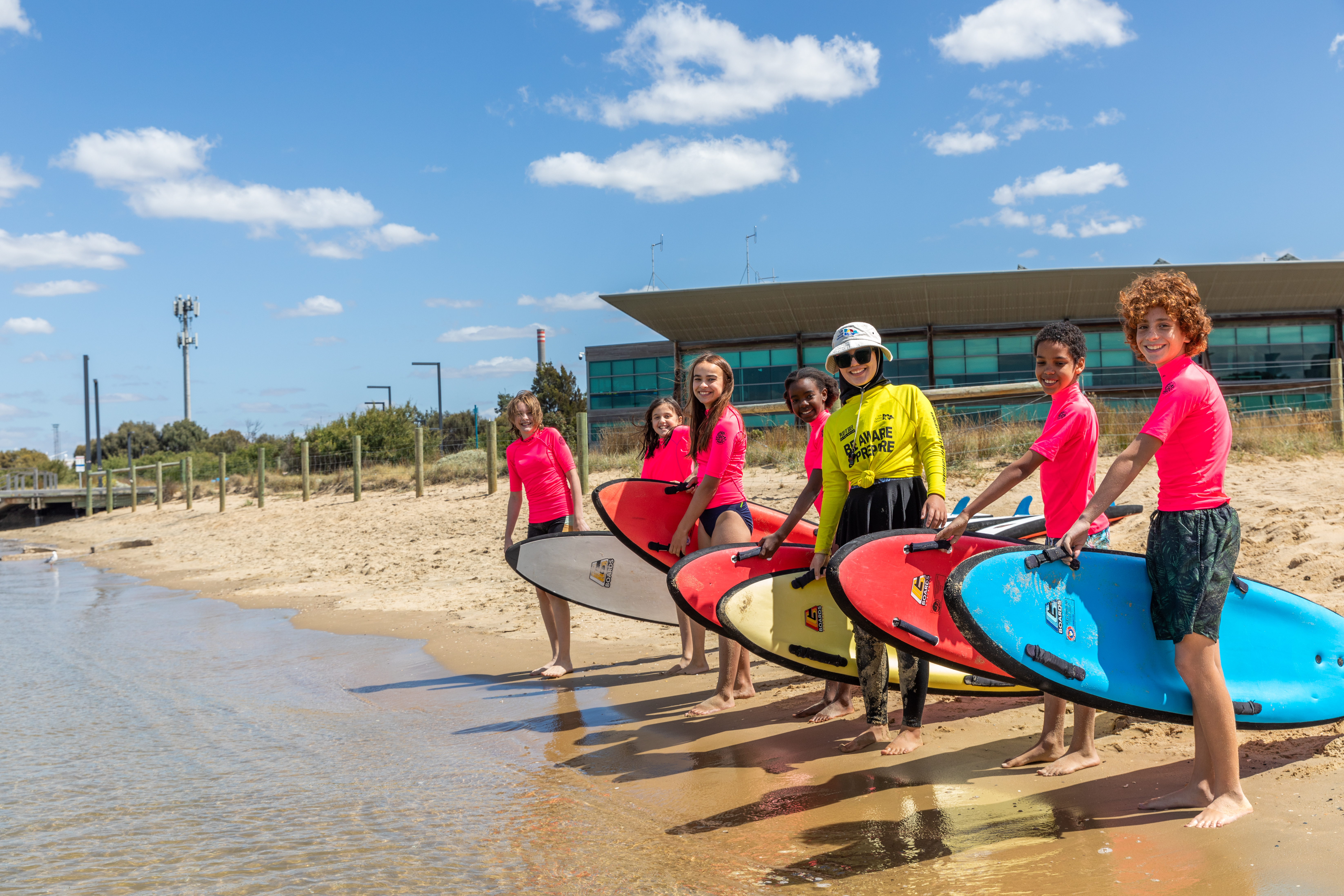 Students line up with surfboards at the beach education program