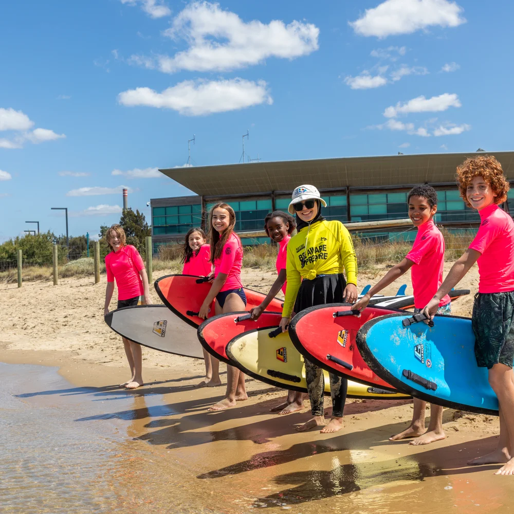 Students line up with surfboards at the beach education program