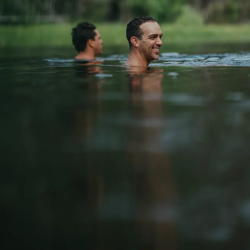 Two people swim together in a river